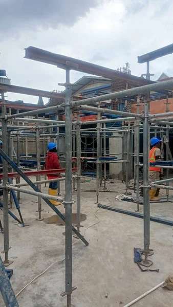 Construction workers on a steel frame and working platform.