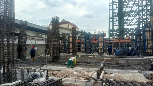 Jakarta, Indonesia - November 27, 2025: Construction workers wearing safety helmets and boots working on a reinforced concrete structure development project at a construction site.