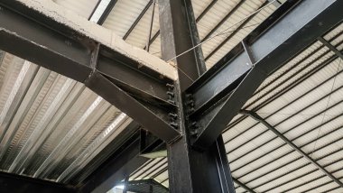 Ayrıntılı yapısal profillere sahip çelik bir binanın çatı iskeleti kirişleri ve sütunları gösteriyor.