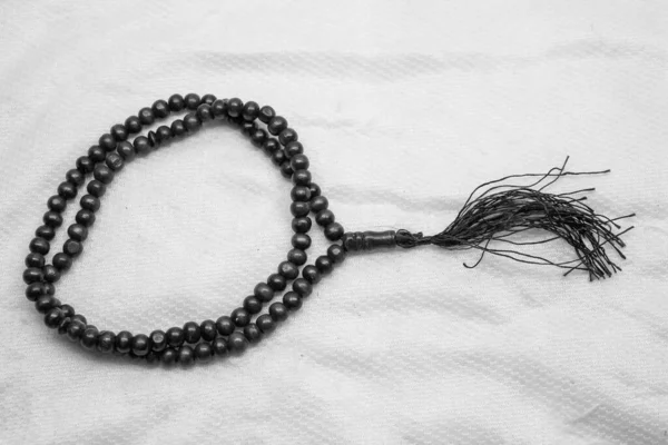 Siyah Müslüman dua boncukları (tasbih) dhikr ve sayma duaları için kullanılır, beyaz bir arkaplan üzerine odaklanır