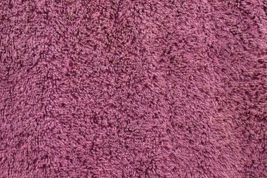 Yumuşak mor morumsu terry havlunun yakın çekim dokusu yoğun liflerle sıcak, parlak ve desenli bir kumaş arkaplan oluşturuyor..