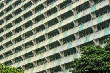 Nane yeşili, krem rengi yatay ve dikey desenli yüksek bir binanın tekrarlanan cephesi ayrıntılı bir geometrik doku oluşturur..