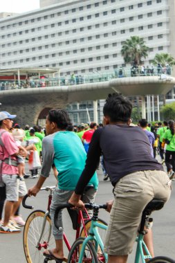 Jakarta, Endonezya - 27 Kasım 2025: Merkez Jakarta 'nın Sudirman bölgesinde ana yolda bisikletle giden Özgür Otomobil Günü katılımcıları, ön planda bisiklet süren iki adama odaklandılar..