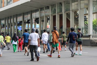 Sakinler kapalı bir otoyolda, Jakarta 'daki ikonik, modern, vahşi mimari yapı kompleksinin arka planında rahatça yürüyorlar..