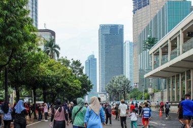 Jakarta, Endonezya - 27 Kasım 2025: Jakarta otoyolunda yürüyen ve egzersiz yapan bir grup insan, ve uzaktaki modern gökdelenler.