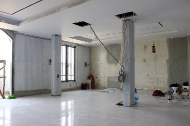 Jakarta, Endonezya - 11 Aralık 2025: Beton bir sütunun üstündeki deliklerden sarkan dağınık elektrik kabloları bitmemiş elektrik tesisatını gösteriyor.