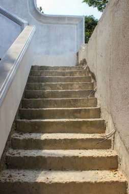 Bitmemiş, pürüzlü ve yıpranmış beton merdivenler beton desenli bir duvarın yanına uzanıyor..