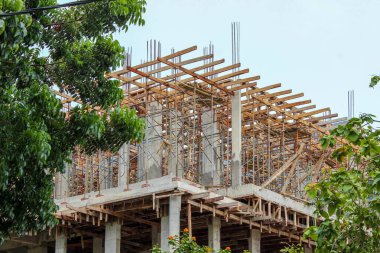 Çelik destek kuvvetleri ve inşaat halindeki bir binanın üst katındaki büyük ahşap iskeleyle güçlendirilmiş beton iskelet..