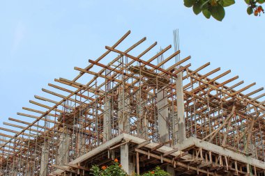 İnşaat halindeki bir binanın üst katlarındaki güçlendirilmiş beton iskeleyi çevreleyen geniş ahşap iskeleler..