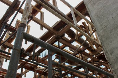 Ahşap biçimlendirme ve çelik iskeleler bir inşaat alanında beton kirişleri ve levhaları desteklemek için aşağıdan görüldü..