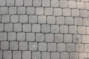 Dışarıdaki gri beton kaldırım bloklarında kare desen düz ve katı zemin yüzeyinde yinelenen bir dokuyu temsil ediyor..