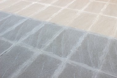 Büyük, desenli desenli, dış döşeme döşemeleri, kısmen temiz ve kısmen açık renkli harç kalıntılarıyla kaplı..