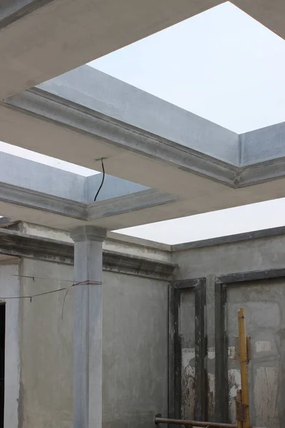 Detail of an open roof structure (skylight structure) and exposed concrete pillars of a building under construction, showing modern minimalist architecture.