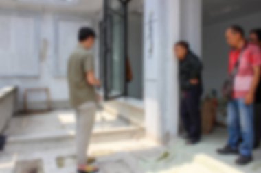 Soyut arkaplan odak dışı. Jakarta, Endonezya - 11 Aralık 2025: İnşaat halindeki bir evin teras alanında pencere çerçevesini ve zemini kontrol eden üç inşaat işçisi.