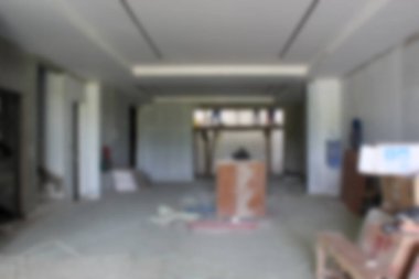 Soyut arkaplan odak dışı. Jakarta, Endonezya - 11 Aralık 2025: Yenileme aşamasında geniş bir oda, gri duvarlar ve bir evin iç inşaat sürecini gösteren muşambayla kaplı bir zemin.