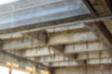 Soyut arkaplan odak dışı. İnşaat alanında, kısmen metal kaplamalarla kaplı, çelik takviyeli, tamamlanmamış beton çatı yapısı..