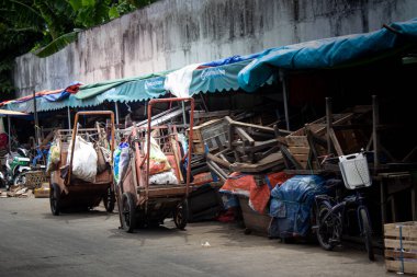 Jakarta, Endonezya - 20 Aralık 2025: Geleneksel bir pazar alanında mavi bir tente çadırının altına park etmiş temizlik işçilerine ait el arabaları.