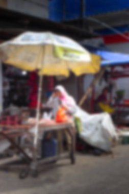 Soyut arka plan odak dışı. Jakarta, Endonezya - 20 Aralık 2025: Bir tesettürlü kadın satıcı markette sarı bir ABC Super Power pil reklam şemsiyesi altında tavuk eti siparişleri hazırlıyor.