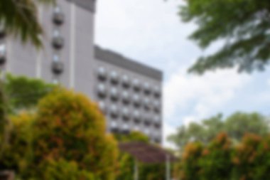 Soyut arka plan odak dışı. Jakarta, Endonezya - 20 Aralık 2025: Avluda birçok küçük balkon ve düzenli Syzygium myrtifolium süs bitkileri ile modern gri otel binası cephesi.