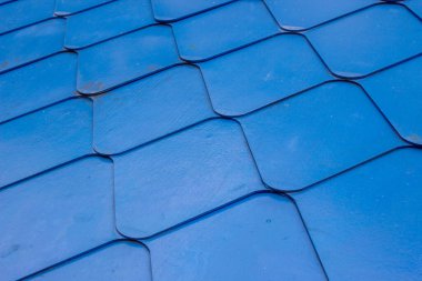 Üst üste binen geometrik şekilli metal veya polimer malzemeden yapılmış parlak mavi ölçekli çatı yapısı.