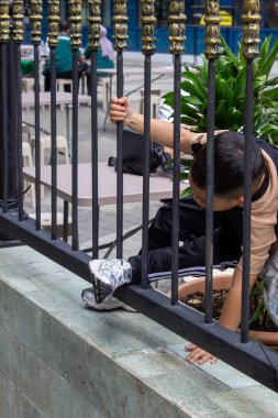Jakarta, Endonezya - 21 Aralık 2025: Orta Cakarta 'da halka açık bir alanda siyah demir çitlere tırmanan genç bir çocuk.