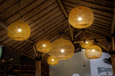 Jakarta, Endonezya - 01 Ocak 2026: Restoranın içini geleneksel bambu çatılarıyla aydınlatan dekoratif rattan asma lambaları sırası.