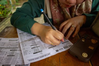 Jakarta, Endonezya - 01 Ocak 2026: Bir kadın Omah Badok menü listesine tahta bir masa üzerindeki kalemle bir sipariş yazar..