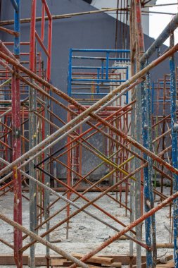 Eski paslı demir iskelenin mavi ve kırmızı renkte çapraz dokusu bir inşaat projesinde geometrik desen oluşturuyor..