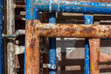 Bir proje sahasında uzun zamandır kullanılan mavi ve turuncu demir iskeletlerdeki pas dokusu ayrıntıları.
