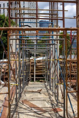 İnşaat alanındaki kavurucu güneşin altında demir iskelelerin düzenlenmesinden oluşan bir koridor..