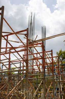 İnşaat projesinde güçlendirilmiş beton sütunlar arasında yüksek katmanlı demir iskeleler.