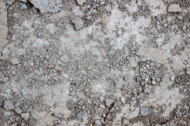 Texture of rocky ground and concrete cement ruins on a building construction site floor in brownish-grey colors.