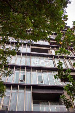 Metalik çerçeveleri ve cam yansımaları olan modern bir apartmanın pencere ve balkon detayları.