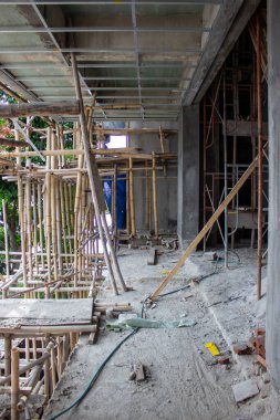 İnşaat halindeki bir binanın manzarası tavan çerçeveleri ve dış yüzeyinde karmaşık bir bambu iskelesi var..