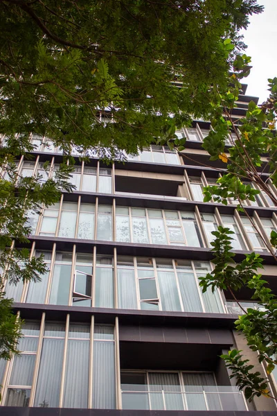 Metalik çerçeveleri ve cam yansımaları olan modern bir apartmanın pencere ve balkon detayları.