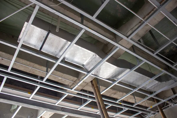 Ticari bir binanın beton tavanına metal tavan iskeleti ve havalandırma boruları yerleştirilmiş..