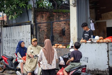 Jakarta, Endonezya - 18 Ocak 2026: Genç bir hindistan cevizi satıcısı Batı Jakarta 'daki Bojong Raya bölgesinde yol kenarında alıcılara hizmet veriyor.