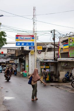 Jakarta, Endonezya - 18 Ocak 2026: Bojong Raya Caddesi atmosferi yağmurdan sonra Indomaret işareti ve dağınık elektrik hatlarıyla ıslandı.
