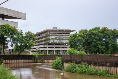Jakarta, Endonezya - 18 Ocak 2026: Graha Ali Sadikin Kembangan binası, nehir kenarındaki yeşil bitkilerle döşenmiş beton cephe.