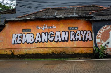 Duvar, Kembangan Raya ve Persija Jakarta logosunun yol kenarındaki sönük ev duvarında olduğunu söylüyor..