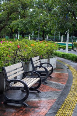 Ahşap ve demirden yapılmış park bankları, Batı Cakarta, Kembangan 'daki körler için dokunsal kaldırım döşemeleri ile donatılmış dairesel bir tasarım..