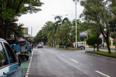 Jakarta, Endonezya - 18 Ocak 2026: Kembangan Raya karayolu trafiği yağmurdan sonra palmiye ağaçları ve Indomaret prizleriyle ıslandı.