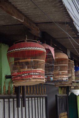 Jakarta, Endonezya - 18 Ocak 2026: Bir evdeki çinko çatının altında asılı geleneksel bambu kuş kafesleri.