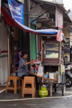 Jakarta, Endonezya - 18 Ocak 2026: Kembangan yol kenarında geleneksel ahşap bir sepetin içinde köfte hazırlayan bir sokak satıcısı.