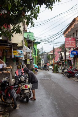 Jakarta, Endonezya - 18 Ocak 2026 Bojong Raya caddesinde elektrik hatlarıyla dolu Honda Scoopy motosikleti organize eden kapüşonlu bir adam.