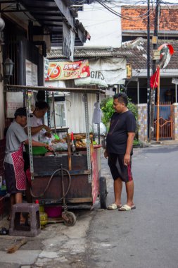 Jakarta, Endonezya - 25 Ocak 2026: Sokak satıcıları bir yerleşim alanındaki yol kenarındaki kızarmış gıda arabasında alıcılara hizmet veriyor.