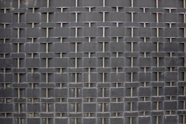 Siyah örülmüş demir çit dokusu simetrik yatay ve dikey desenlerle bir bina üzerinde modern ve endüstriyel bir izlenim yaratıyor..