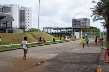 Jakarta, Endonezya - 25 Ocak 2026: West One City Jakarta 'nın geniş park alanında çıplak ayakla futbol oynayan bir grup çocuk.