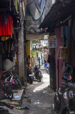 Jakarta, Endonezya - 25 Ocak 2026: Çocuk bisikletleri, kurutma giysileri ve dağınık elektrik hatlarıyla dolu yoğun bir yerleşim bölgesinde dar bir sokak.