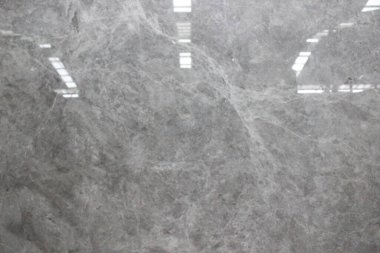 Tarafsız gri yüzeyi ve ince beyaz damarları eşit yayılmış cilalanmış Tundra Gri mermer dokusu.
